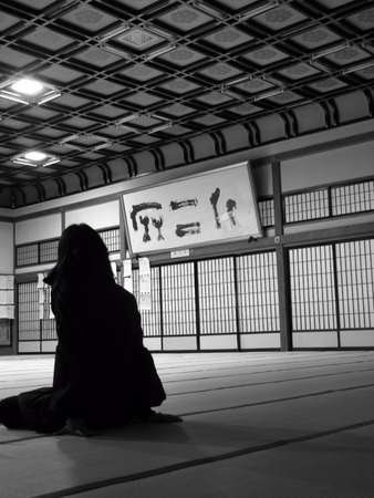 A Japanese woman sits in a tatami room with sliding doors and calligraphy around herの写真素材