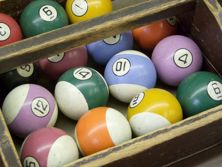 Old, worn billiard balls sit organized in a tray