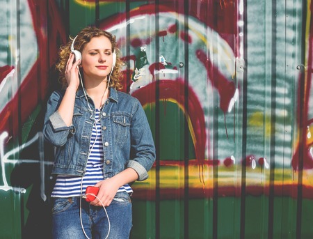 Young Hipster curly woman using her phone in the city