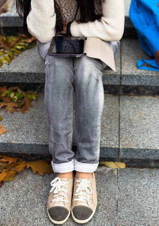 Teenage student using tablet in autumn city parkの写真素材
