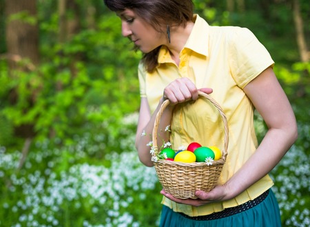 Young woman with Basket of easter eggs on meadow, Closeup pictureの写真素材