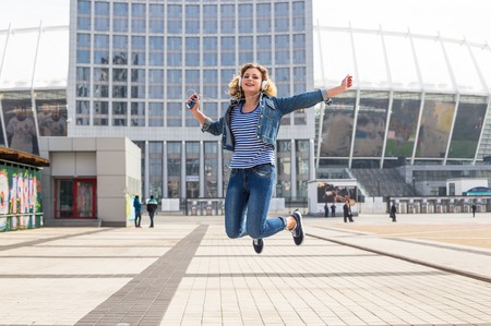 Hipster teen girl looking to her phone and listening musicの写真素材