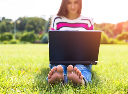 Student working on laptop in park. Summer weather