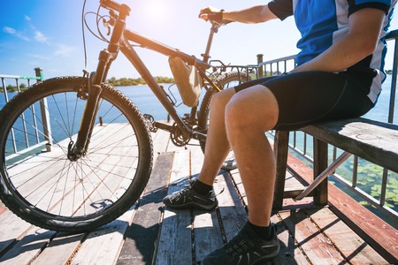 Bicyclist relax in a pear near river. Sunny summer hot day.の写真素材