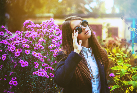 Beautiful woman in black glasses posing near flowerbedの写真素材