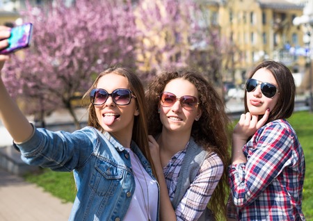 Young happy hipster teenage girls having fun in summer park