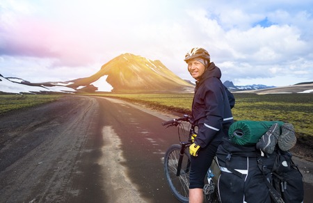 Happy biker on backdrop of lake and snowing mountainsの写真素材