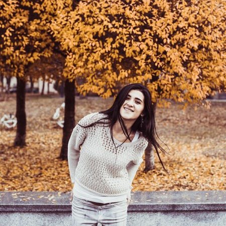Young happy teenage girl having fun in autumn city park. Fall life-style pictureの写真素材