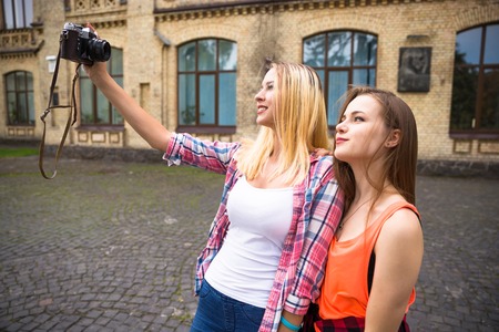 Young happy teenage girls having fun in city park. Good summer weather. Girlfriends walking in park.の写真素材