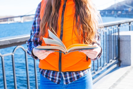 Happy teenage girl read a book and time in the city