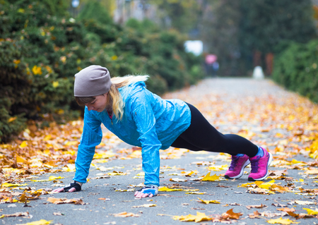 Young sport woman doing exercises during autumn training outsideの写真素材