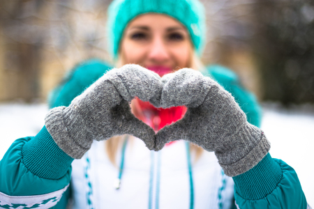 Young happy woman make heart with hands in winter city park outdoor.の写真素材