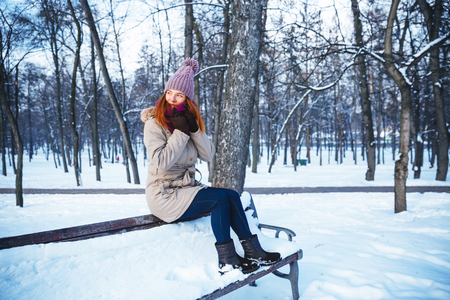 Happy redhead woman walking in winter park and enjoy the snowの写真素材
