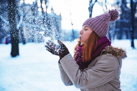 Happy redhead woman walking in winter park and enjoy the snowの写真素材