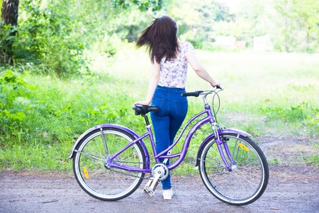 Happy pretty young girl bicycling on summer park. Happy relax time in city. Beautiful woman, sunny dayの写真素材