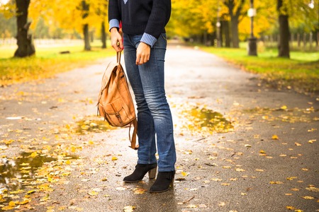 Happy woman walking at the rain in beautiful autumn park.