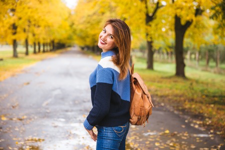 Happy woman walking at the rain in beautiful autumn park.の写真素材