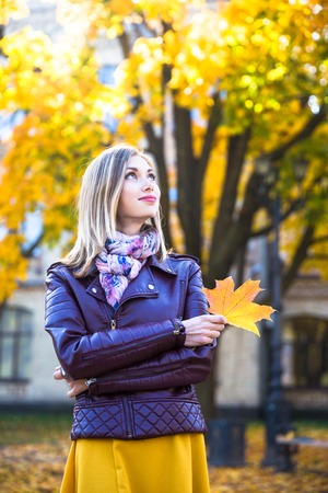 Happy teen girl with yellow leaf smile during walking on autumn park. Fall conceptの写真素材