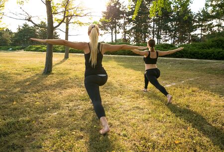 Sport women doing yoga outside in morning. Fitness girls relax in parkの写真素材