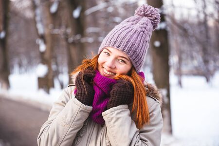 Happy redhead woman walking in winter park and enjoy the snowの写真素材
