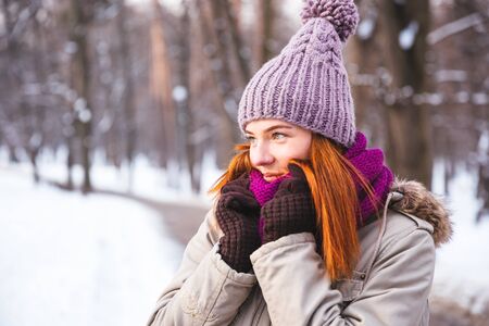 Happy redhead woman walking in winter park and enjoy the snowの写真素材