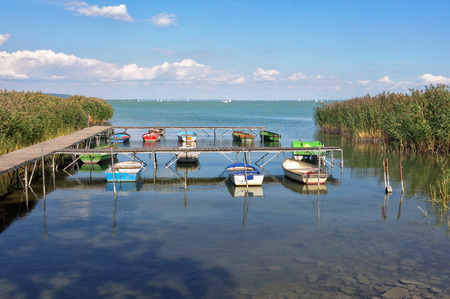Small fishing and rowing boats tied to the pier between reeds on Lake Balaton at Tihany, Hungaryの写真素材