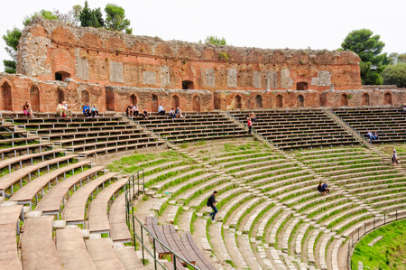 Tourists sit on the grandstand and admire the remnants of the ancient Greek theatre - Taormina, Sicily, Italy, 22 October 2011のeditorial素材