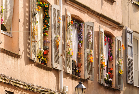Windows and shutters decorated with colorful fake flowers - Grasse, Franceの写真素材