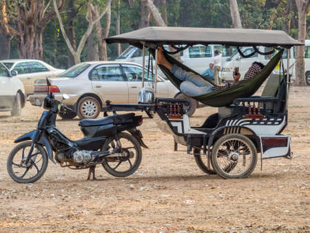 Relaxing tuk tuk driver waiting for his passengers in the Angkor Wat car park - Siem Reap, Cambodiaのeditorial素材