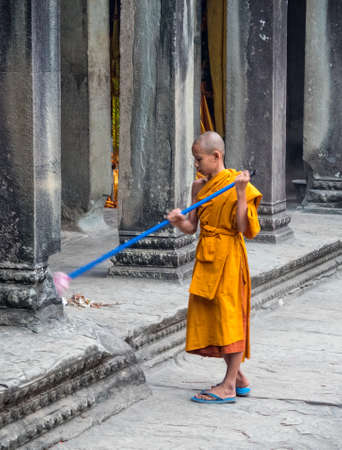 Young monk in orange robe sweeping early morning at Angkor Wat - Siem Reap, Cambodiaのeditorial素材