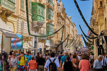 Tourists and locals walk along the Republic Street, the main street of the city - Valletta, Malta
