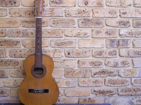 Old Country Guitar resting on wallの写真素材