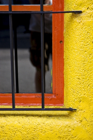  old red window and iron grate in a yellow wall in the centre of buenos aires argentinaの写真素材