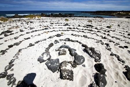 spiral of black rocks in the white  beach  in lanzarote spain