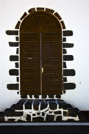 brass brown knocker in a brown closed wood  door and white wall lanzarote abstract  spain canariasの写真素材