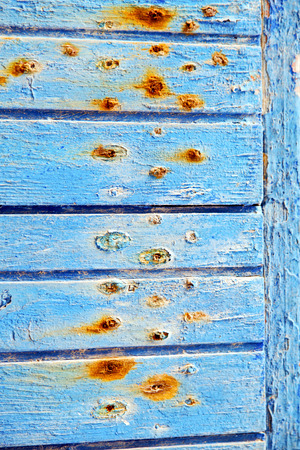 stripped paint in the blue wood door and rusty nailの写真素材
