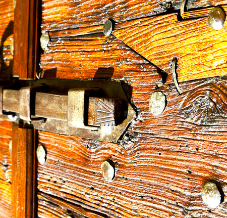 italy  patch lombardy    cross castellanza blur   abstract   rusty brass brown knocker in a  door curch  closed woodの写真素材