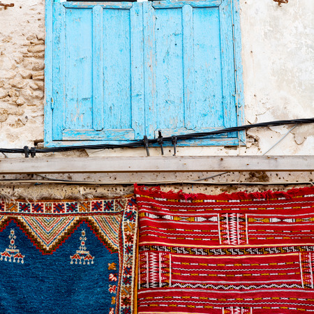 blue window in morocco africa old construction and brown wall red carpetの写真素材