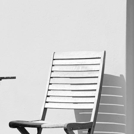 chair and stone pavement in the greece island of paros old bench near a brick antique wallの写真素材