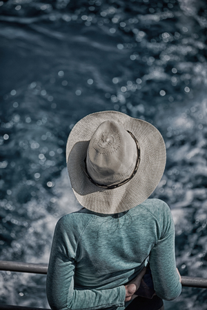 unknown woman with hat looking at the ocean like vacation conceptの写真素材