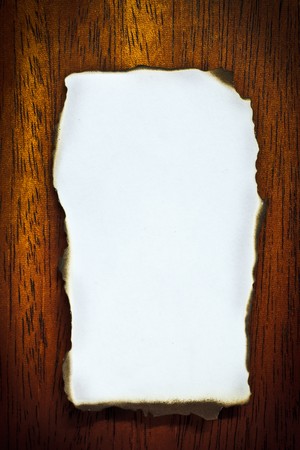 Burn edge blank paper on brown wood texture (mahogany)の写真素材