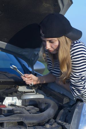 Car on roadside and young woman attempting to repair it