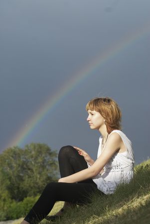Young woman and rainbow after rainの写真素材