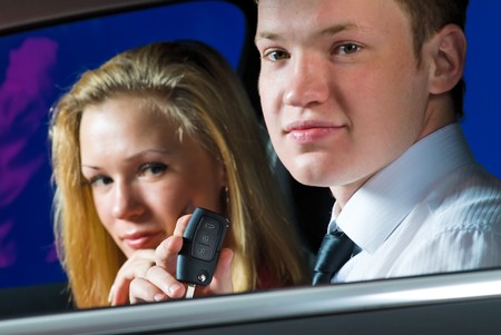 Happy young family sitting in black car looking out windows