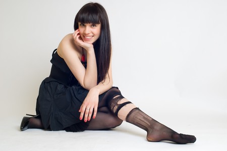 Young sexy brunette woman in torn stockings at white backgroundの写真素材