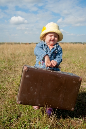 Young beautiful girl with suitcase at country sideの写真素材