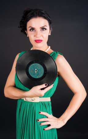 Young beautiful woman holding musical disc at black backgroundの写真素材