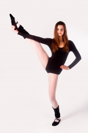 Young cute woman in gymnast suit show athletic skill at white backgroundの写真素材