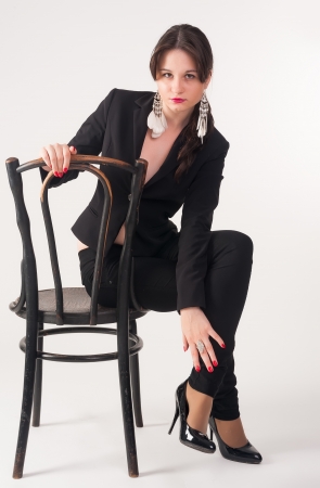 young gorgeous caucasian brunette on the chair at white, studio shotの写真素材