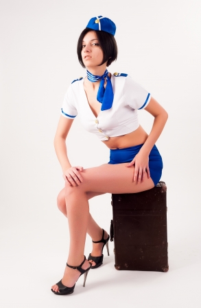 Attractive young stewardess sitting on old-fashioned suitcaseの写真素材